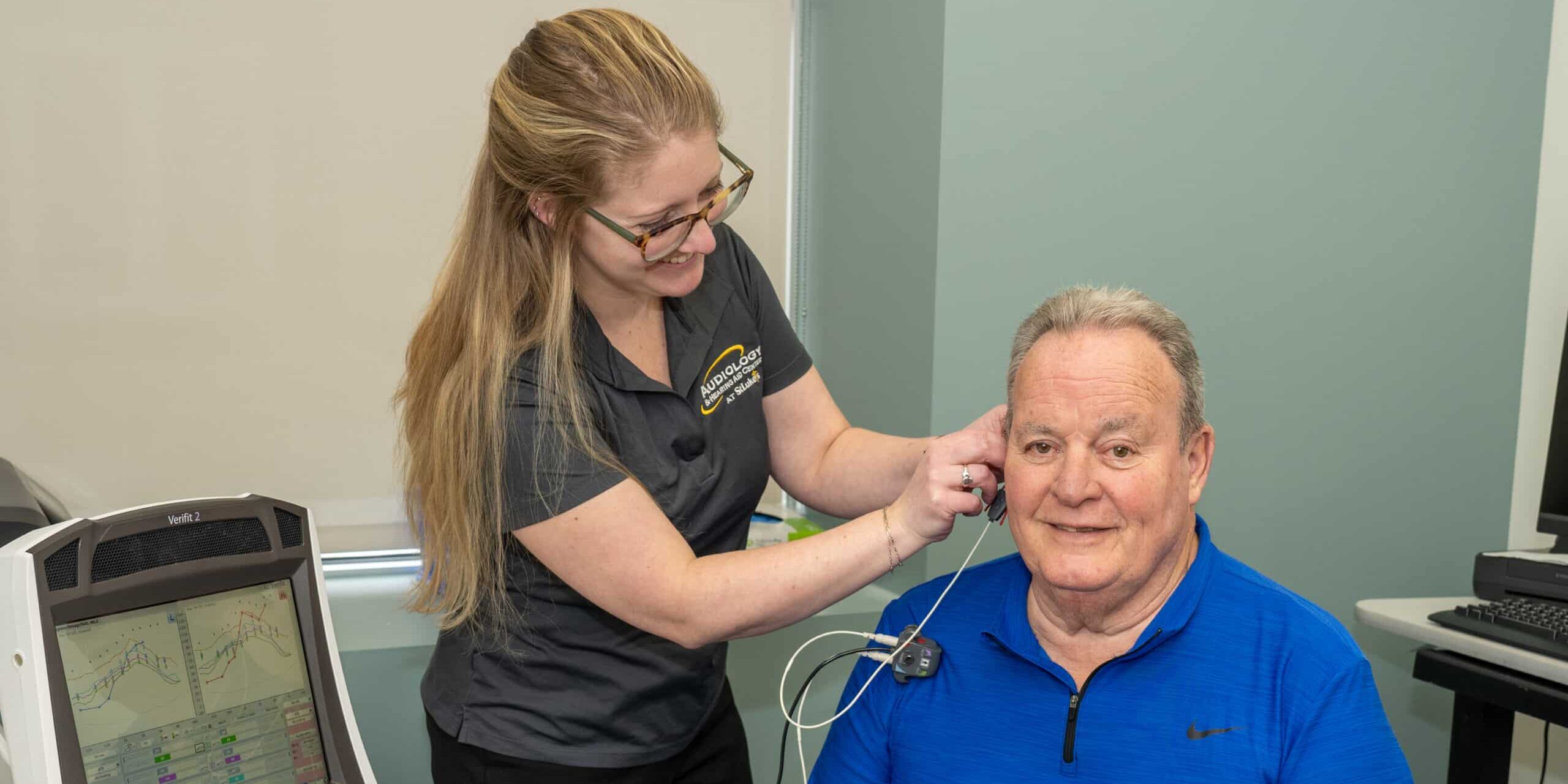 One of our expert audiologists performs hearing testing on a patient, who is seated